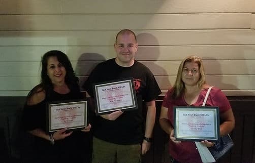 Three graduates holding their trainer certification awards